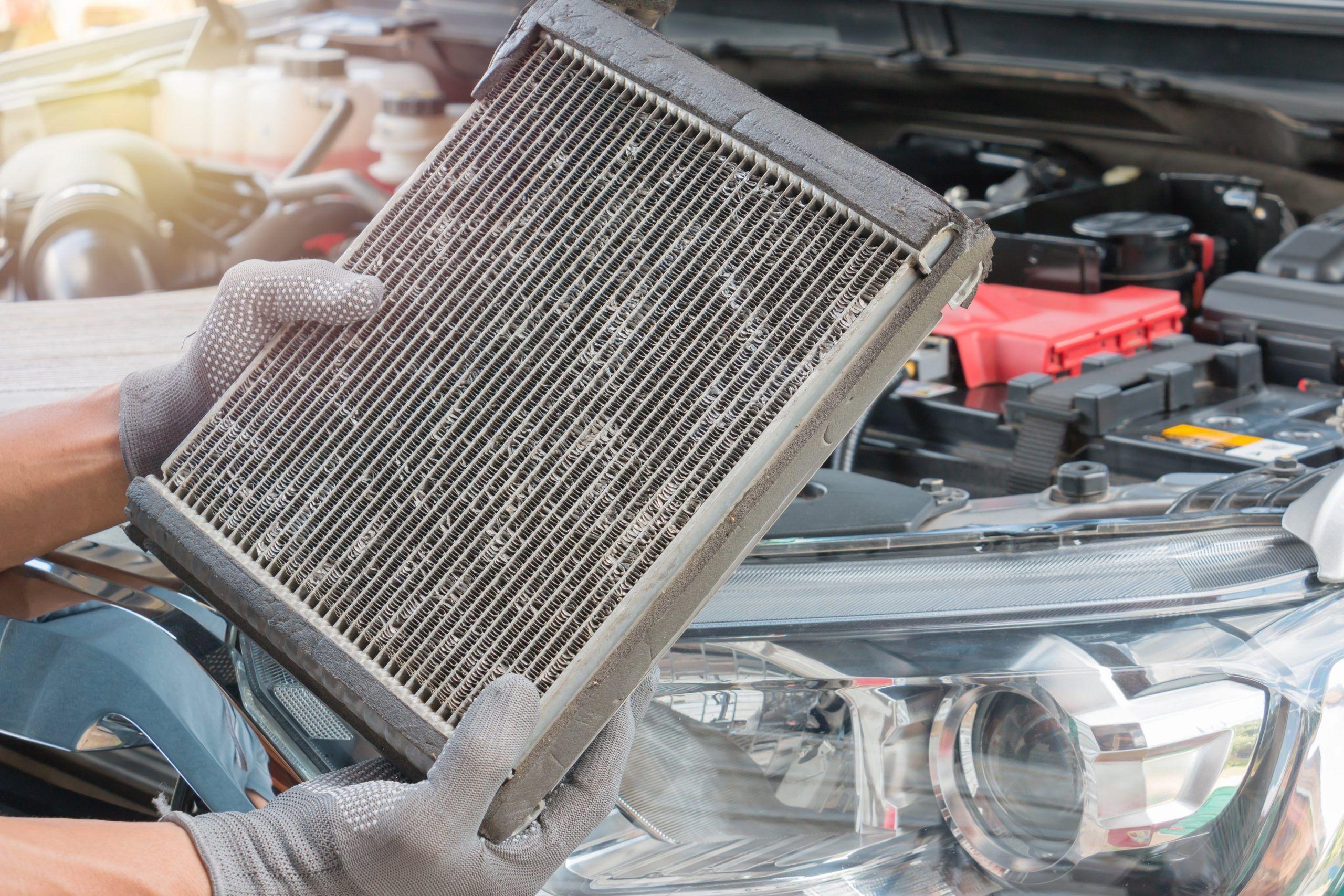 Mechanic holding a dirty, clogged heater core, a common cause of car heater failure.