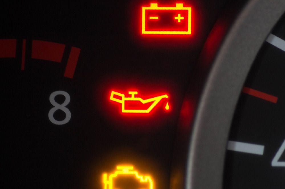 Car dashboard showing an illuminated oil warning light, signaling low engine oil levels.