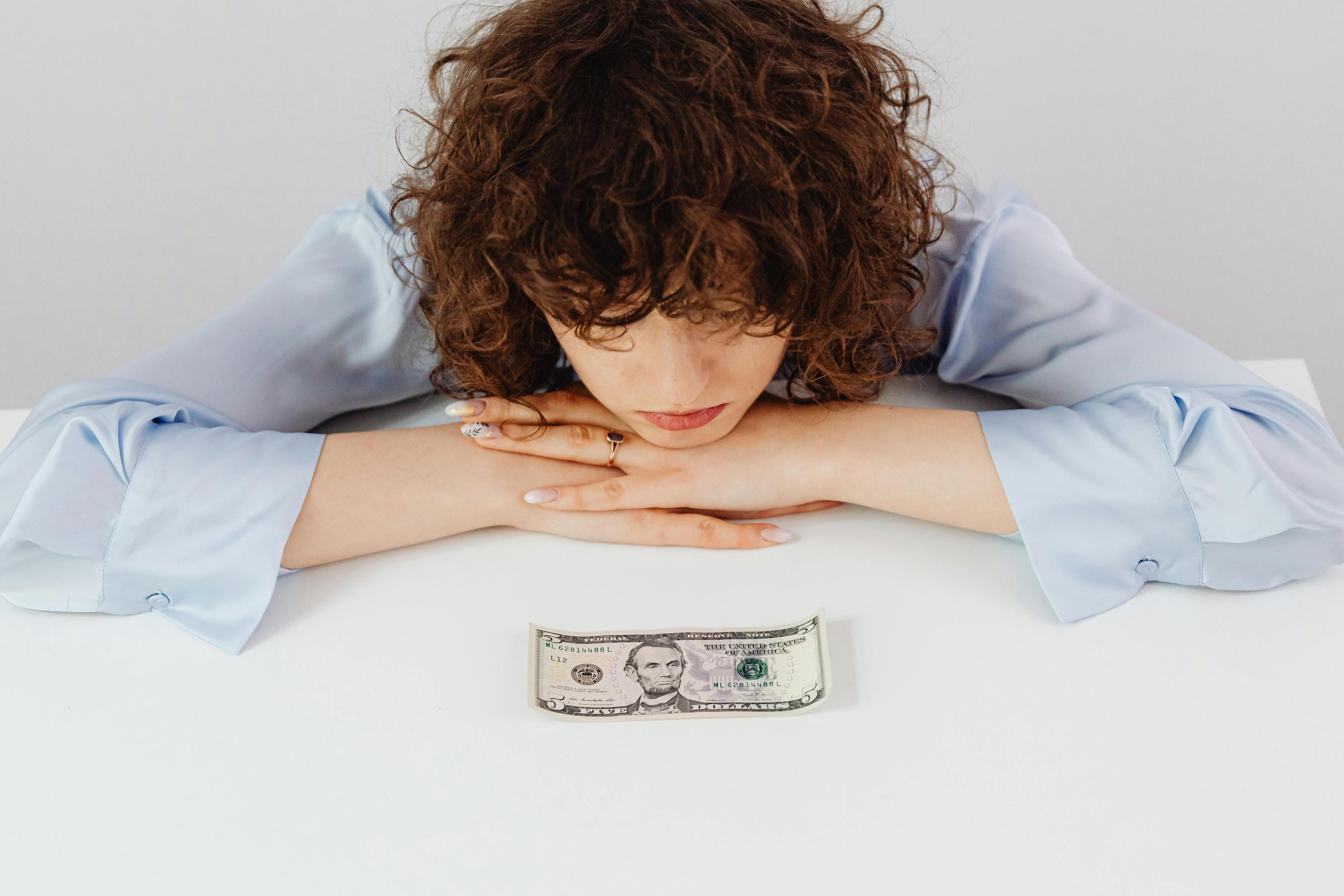 Why Car Prices Still Feel High in 2026: Affordability and Financing Pressure Explained Woman staring at money on a table