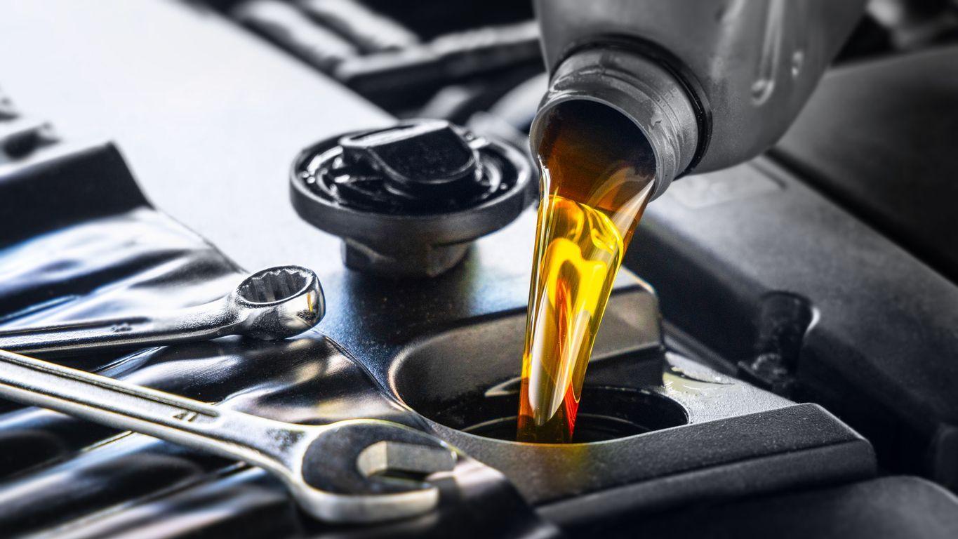 Fresh motor oil being poured into a car engine to maintain lubrication in cold weather.